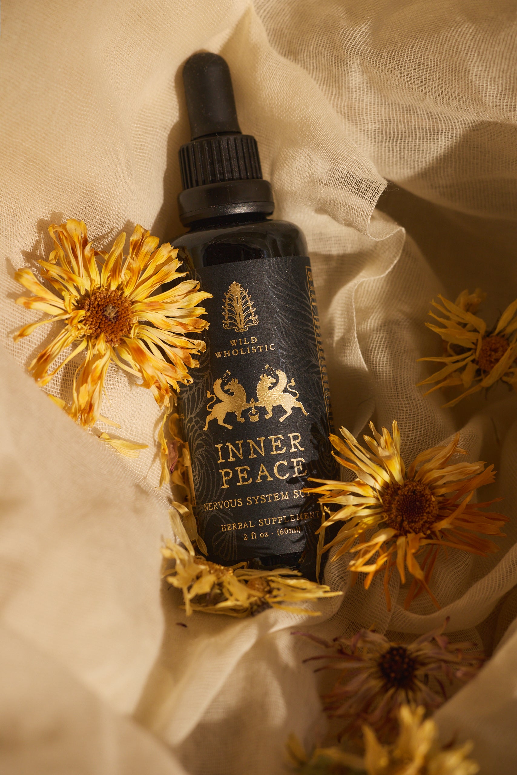 Bottle of 'Inner Peace' with dropper on a beige fabric background with yellow flowers
